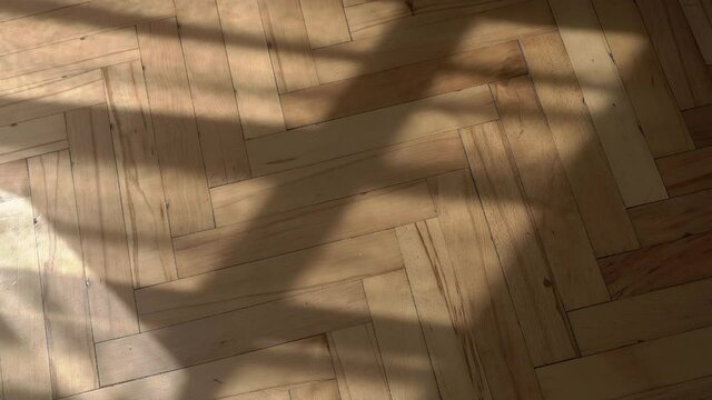 Wooden floor with shadows from the window background. Wooden parquet floor in vintage retro room in morning sunlight. Empty vintage old interior with moving shadows of curtains