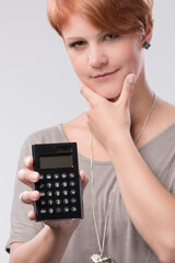 Young red haired woman is using a calculator 