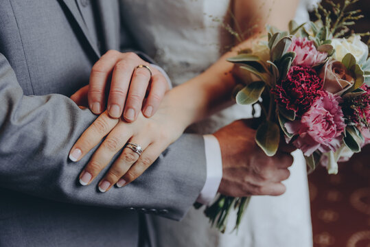 stylish bridal couple together, hands with wedding rings close up