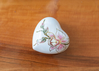 Obraz na płótnie Canvas Vintage heart shape porcelain box with orchid pattern on a wooden table