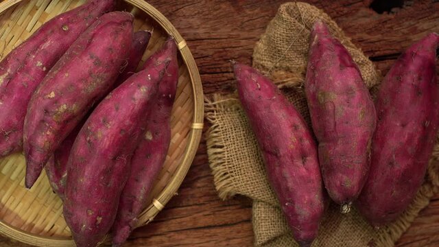 Japanese sweet potatoes or Beni Haruka on wooden background. Flat lay of sweet potatoes on wooden floor with good lighting. Shooting in studio for advertisement. 