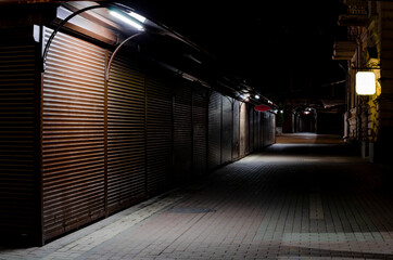 indoor empty street market steel roller shutters. night deserted lane. street vendors