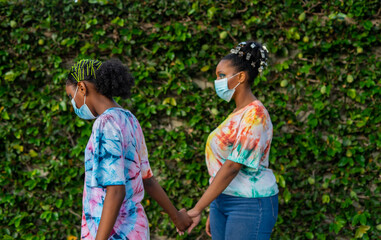 Young black girls in masks and holding hands