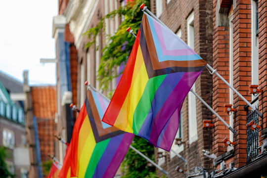 Progress pride flag (new design of rainbow flag) waving in the air with blue sky, Symbol of Gay, Lesbian, Bisexual and Transgender, LGBT community in Holland, Social movements, Amsterdam, Netherlands.
