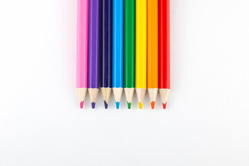 colored pencils lie in a row on a white background