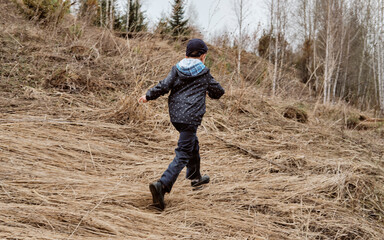 teenage boy in rural path among autumnal trees in forest walking away back view