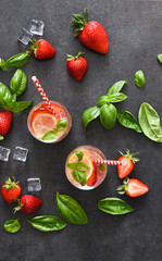 Summer drink. Cold lemonade with strawberries and basil on a concrete background.
