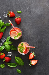 Summer drink. Cold lemonade with strawberries and basil on a concrete background.