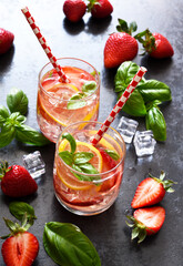 Summer drink. Cold lemonade with strawberries and basil on a concrete background.