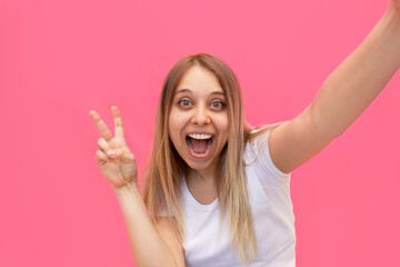 A young pretty caucasian impressed excited smiling cheerful blonde woman in a white t-shirt takes...