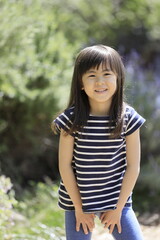 Naklejka premium 緑の中の女子小学生(6歳)の笑顔