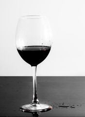 Glass of red wine on the table. Drops of wine on the table.