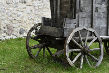 Part of an old cart. Gray boards and gray cart wheels. 