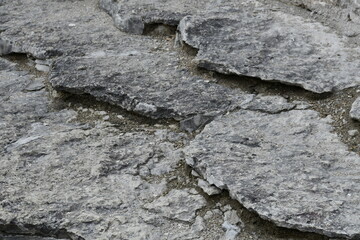 Natural stone surface in the form of scales. Gray flat stones lie on top of each other. 
