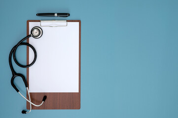 Fototapeta na wymiar Blank medical clipboard, stethoscope and pen on light blue background with copy space.