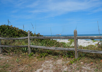 Fototapeta premium Old weathered wooden fence in front of the sand dunes with the ocean in the back round