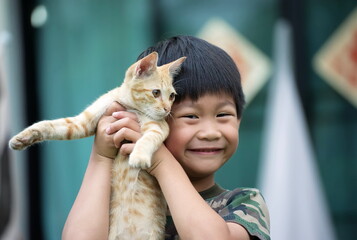Happy little asian boy holding a kitten : looking at camera