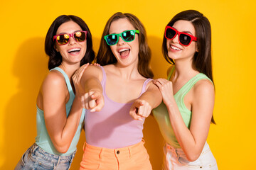 Photo of young beautiful excited crazy smiling funky girls in sunglass point finger you isolated on yellow color background