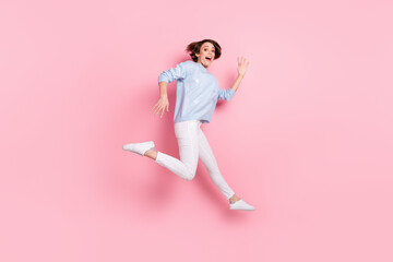 Fototapeta na wymiar Full size photo of smiling crazy excited girl jumping showing hands say hello greetings isolated on pink color background