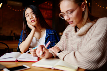 Thoughtful women doing homework in cafe