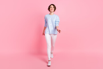 Full size photo of happy cheerful good mood lovely girl go walk wear blue sweater and white pants isolated on pink color background