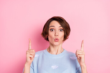 Photo of shocked girl direct fingers up empty space unexpected promo isolated on pink color background