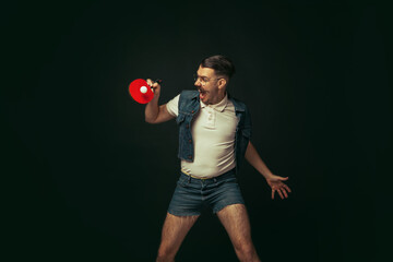 Young caucasian man playing tennis isolated on black studio background in retro style, action and motion concept