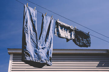 Blue jeans and boxer shorts drying on backyard clothes or washing line.