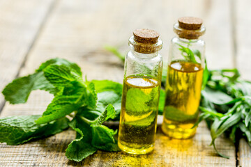 organic oil in bottle with rosemary and mint on light table background