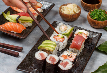 Close up of hand taking roll with chopsticks from a plate