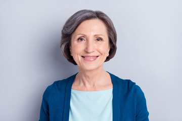 Portrait of attractive cheerful middle-aged woman wearing blue cardigan isolated over grey color background