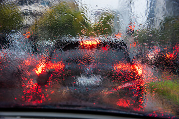 Looking through a wet drivers window at traffic while stopped on a rainy morning rush hour