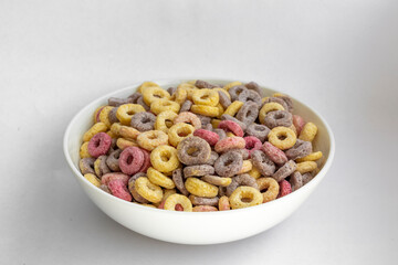 A bowl of colourful loops cereals against a white background 