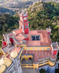 Aerial view of Pena Castle clock tower with forest in background, view of the Romanticist castle on hilltop, Sintra, Lisbon, Portugal.