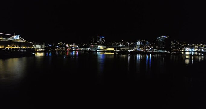 Aerial crane motion of Oslo harbor at night from illuminated Opera House