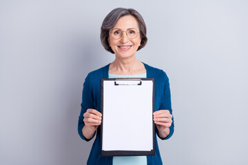 Portrait of attractive cheerful woman holding in hands empty blank copyspace clipboard isolated over grey pastel color background