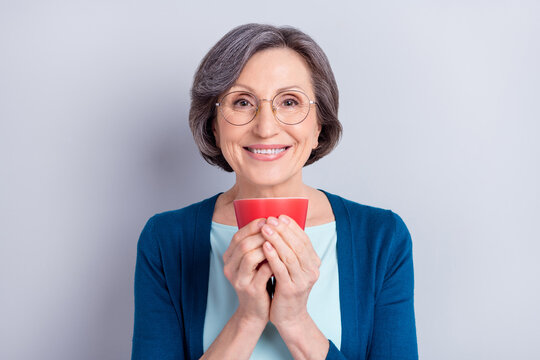 Portrait of attractive cheerful woman drinking beverage enjoying hot milk isolated over grey pastel color background
