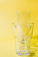 Several empty glasses of different shapes in a row in a yellow-gray palette. Inclusiveness concept. Vertical view