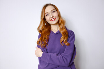 Portrait of a smiling red-haired woman in a purple hood on a white background