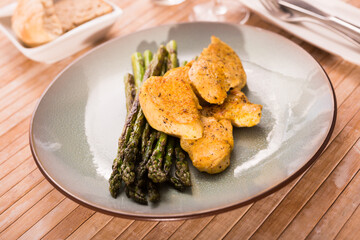 fried chicken breast pieces with asparagus on plate