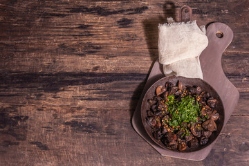 Fried royal champignons in an old cast-iron skillet with trendy hard light, dark shadow