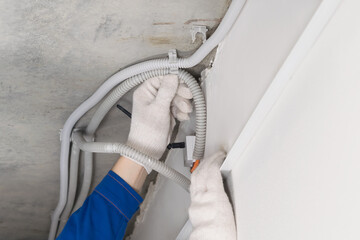 a worker in a helmet lays the cable in the false ceiling, close-up