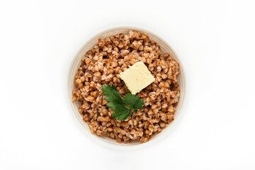 Buckwheat porridge in bowl with parsley leaf and butter isolated in white background. Gluten free ancient grain for healthy diet. Top view. Copy space.
