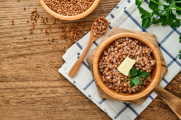 Buckwheat porridge in bowl with parsley leaf and butter on old wooden background. Gluten free ancient grain for healthy diet. Top view. Copy space.