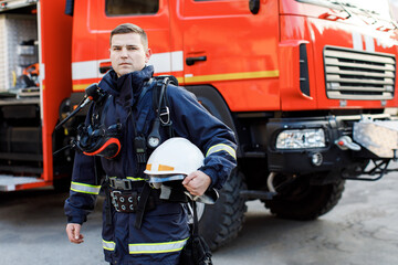 Portrait of caucasian Firefighter in uniform and helmet near fire engine.