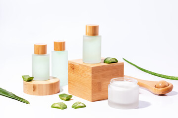 Fototapeta na wymiar Natural plant based cosmetics with aloe on wooden podiums in reusable bottles with plant shadow on background