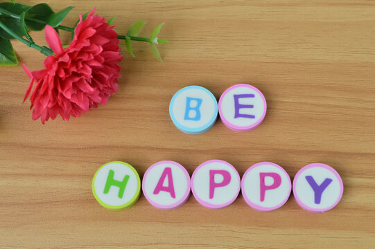 Top view of flower and alphabet letters with text BE HAPPY. Conceptual image