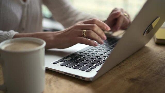 Businesswoman typing and using laptop at table during working day at home office.
