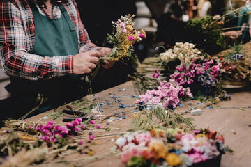 Florist working on a bouquet of flowers in front of a table with tools