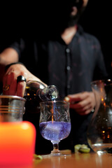 Professional bartender preparing drink with ice and fruits